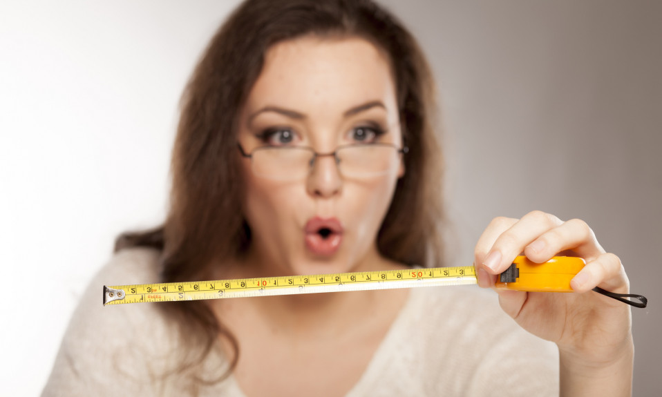 young woman is stunned by the size shown on the measuring tape